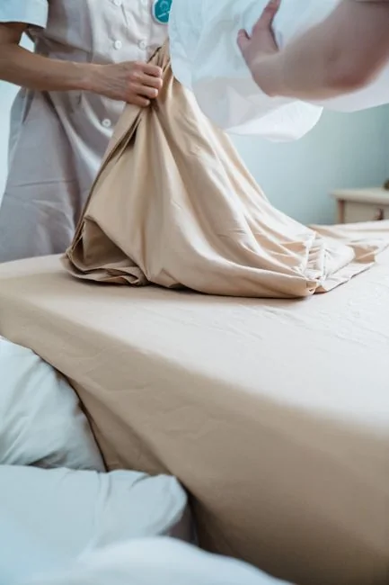 image-héros Individual in protective gear cleaning microwave using spray bottle and cloth indoors.